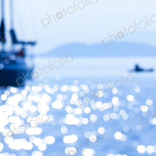 Defocussed view of a sailing boat on the water with a small tender boat.