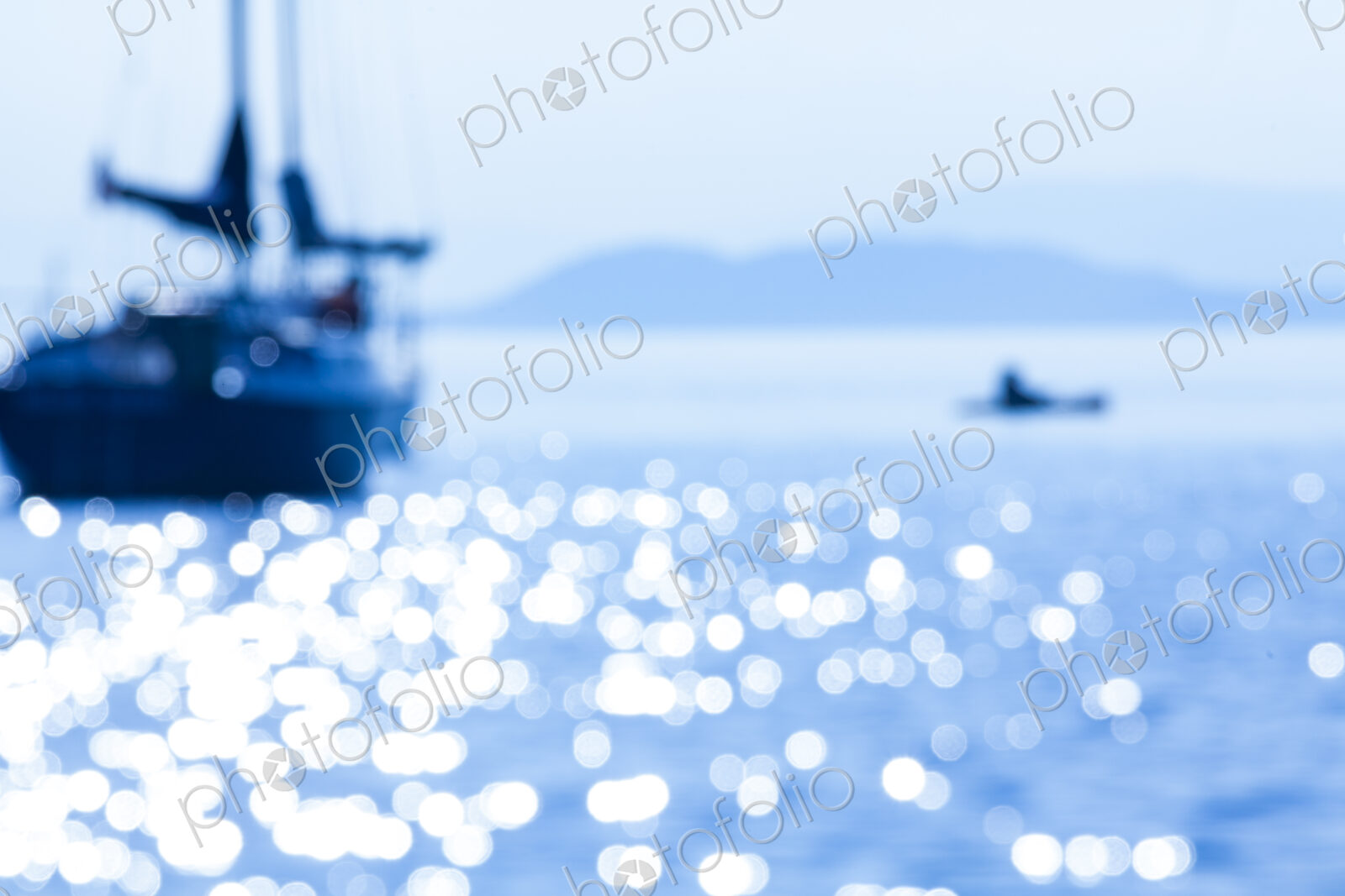 Defocussed view of a sailing boat on the water with a small tender boat.