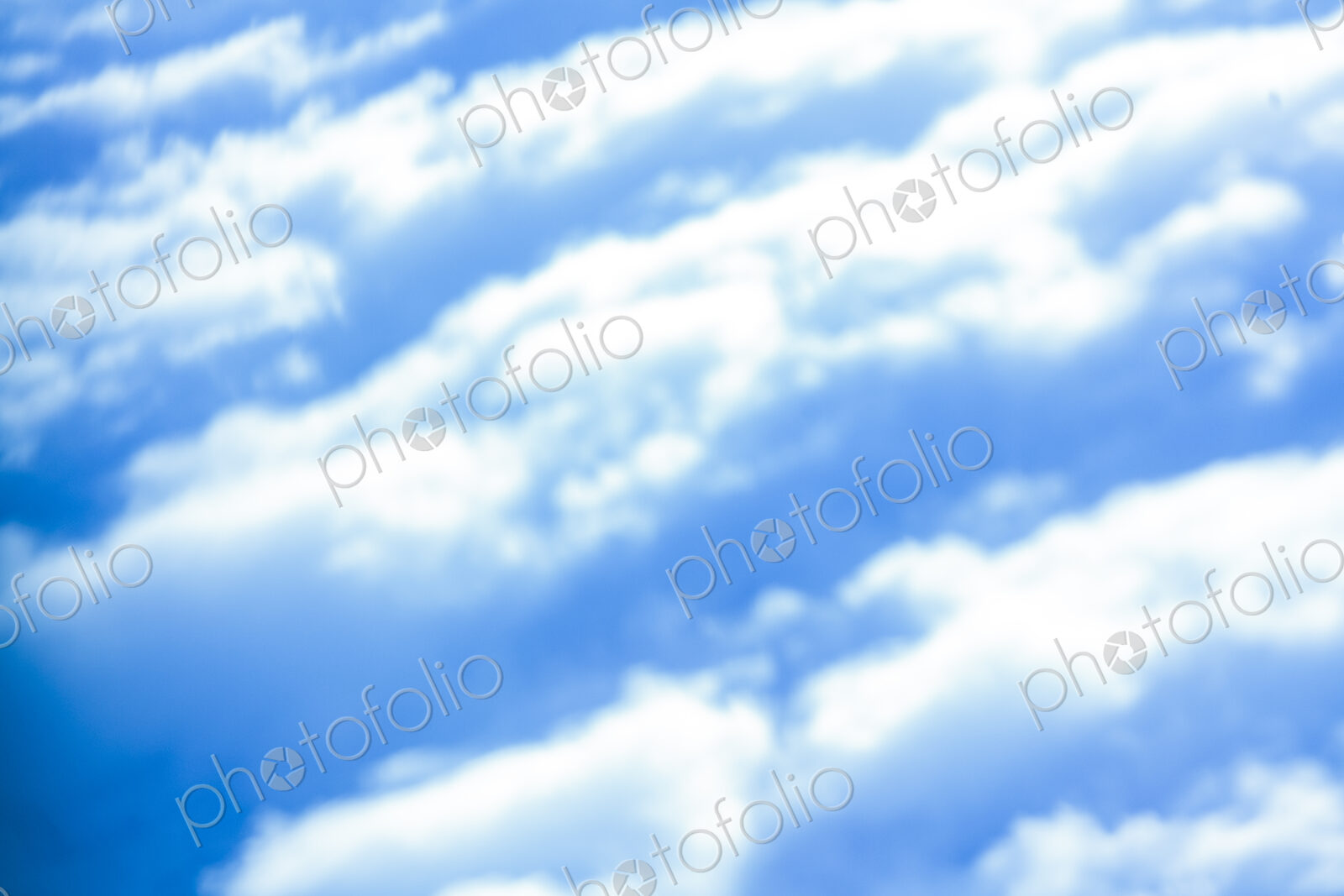 Defocussed view of fluffy clouds in a blue sky.