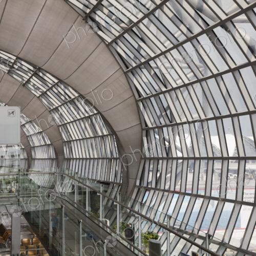Departure gate at Bangkok Airport, an elevated view of a curved glass terminal wall…