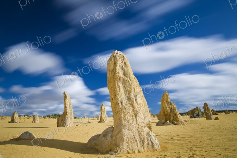 Desert landscape dotted with limestone pinnacles under a cloudy sky.