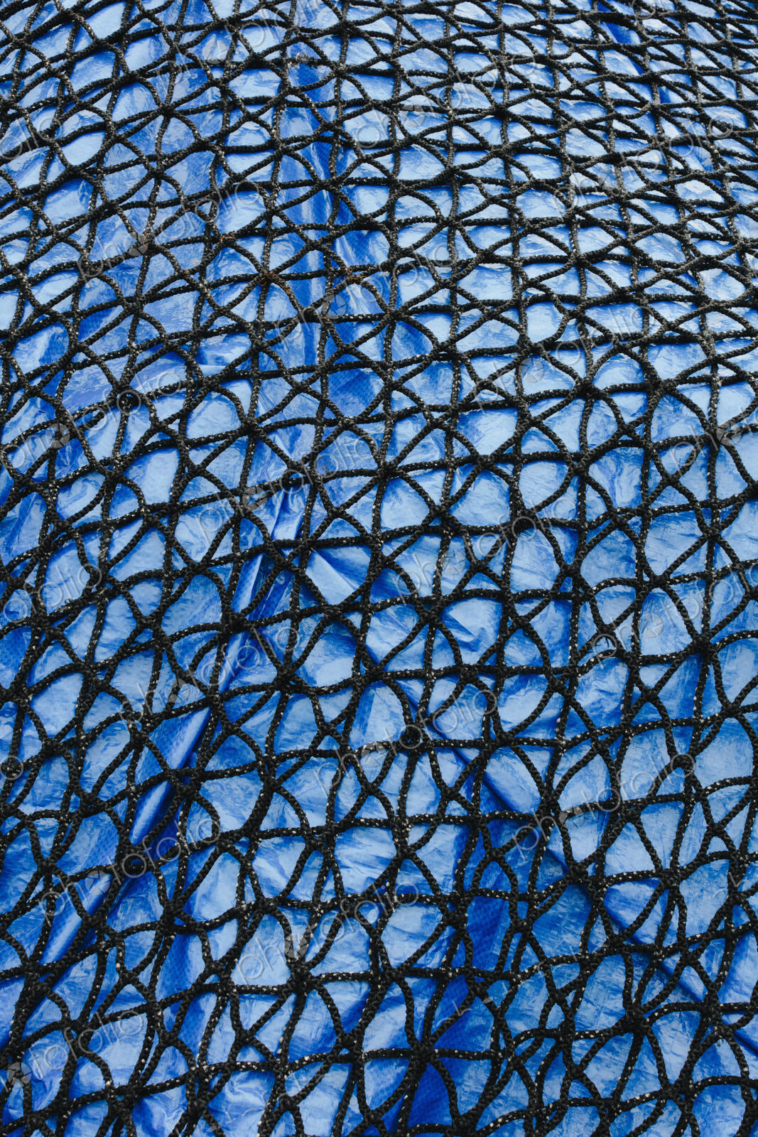 Detail of commercial fish net covering blue tarpaulin
