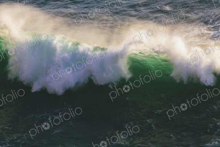 Detail of crashing waves, surf and crest, windblown mist curling from the white water,…