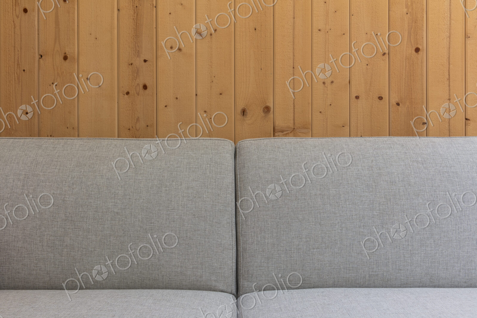 Detail of modern couch against a wood panel wall
