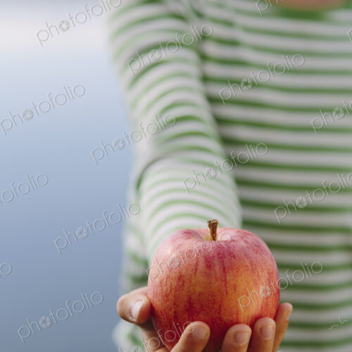 Detail of nine year old girl holding organic apple Detail of nine year old girl holding organic apple
