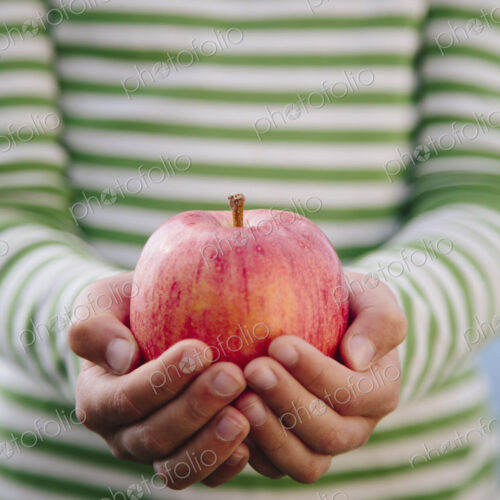 Detail of nine year old girl holding organic apple Detail of nine year old girl holding organic apple