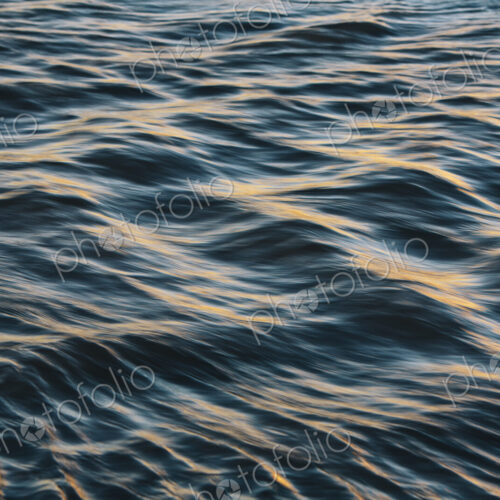 Detail of sunlight reflecting on small waves on water surface.
