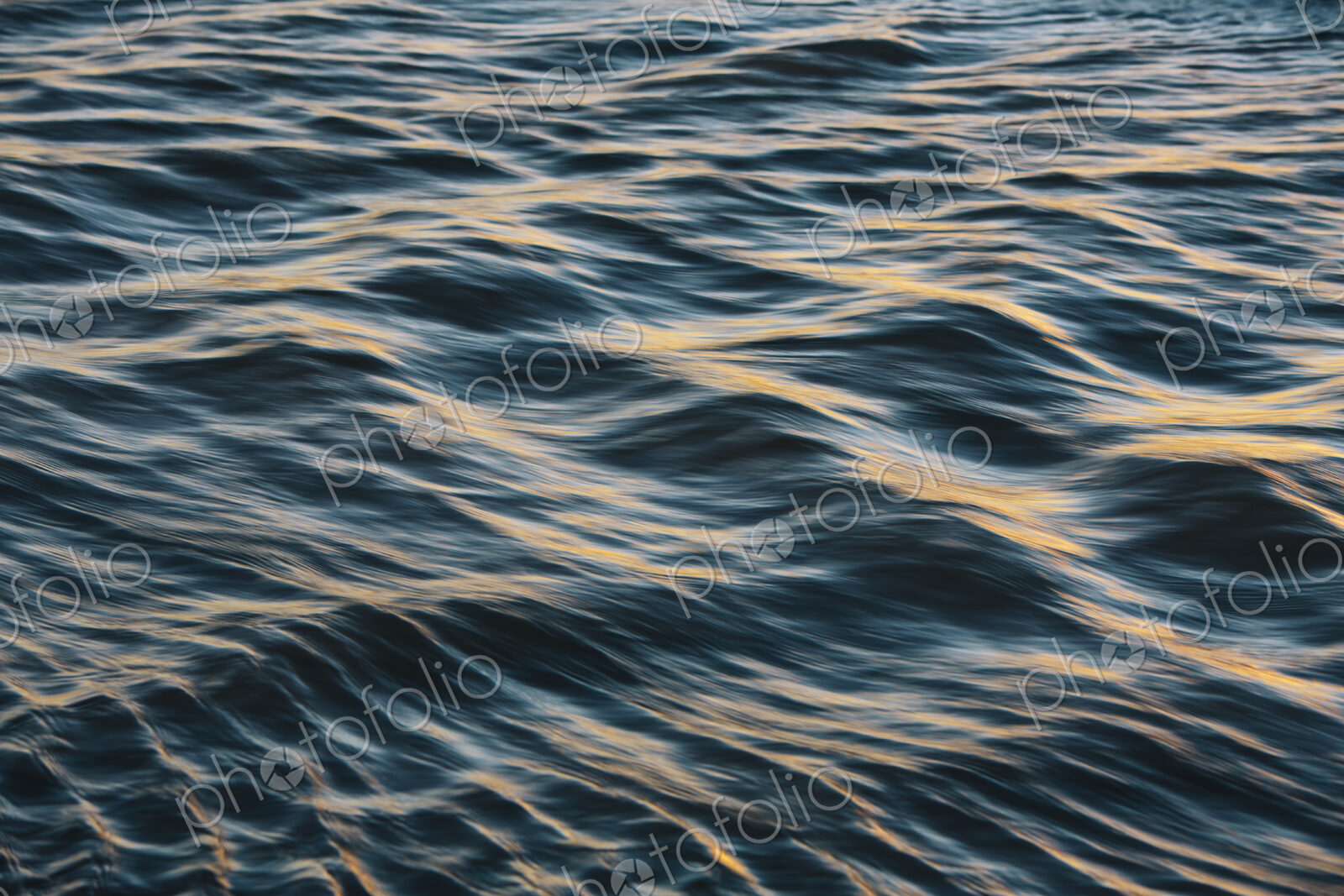 Detail of sunlight reflecting on small waves on water surface.