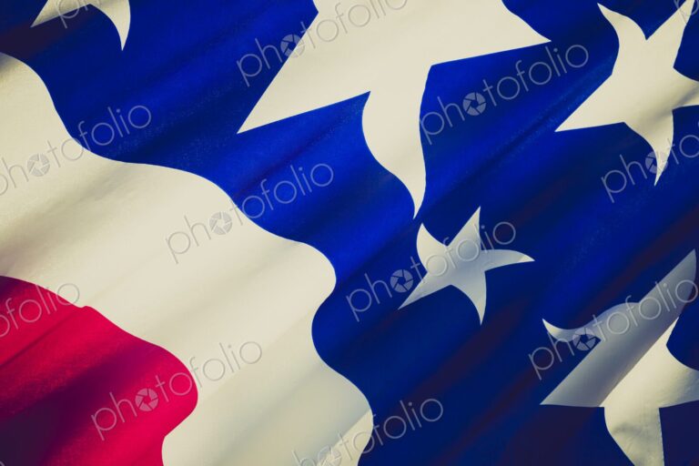 Detailed close-up of the United States flag showing stars and stripes in red, white,…
