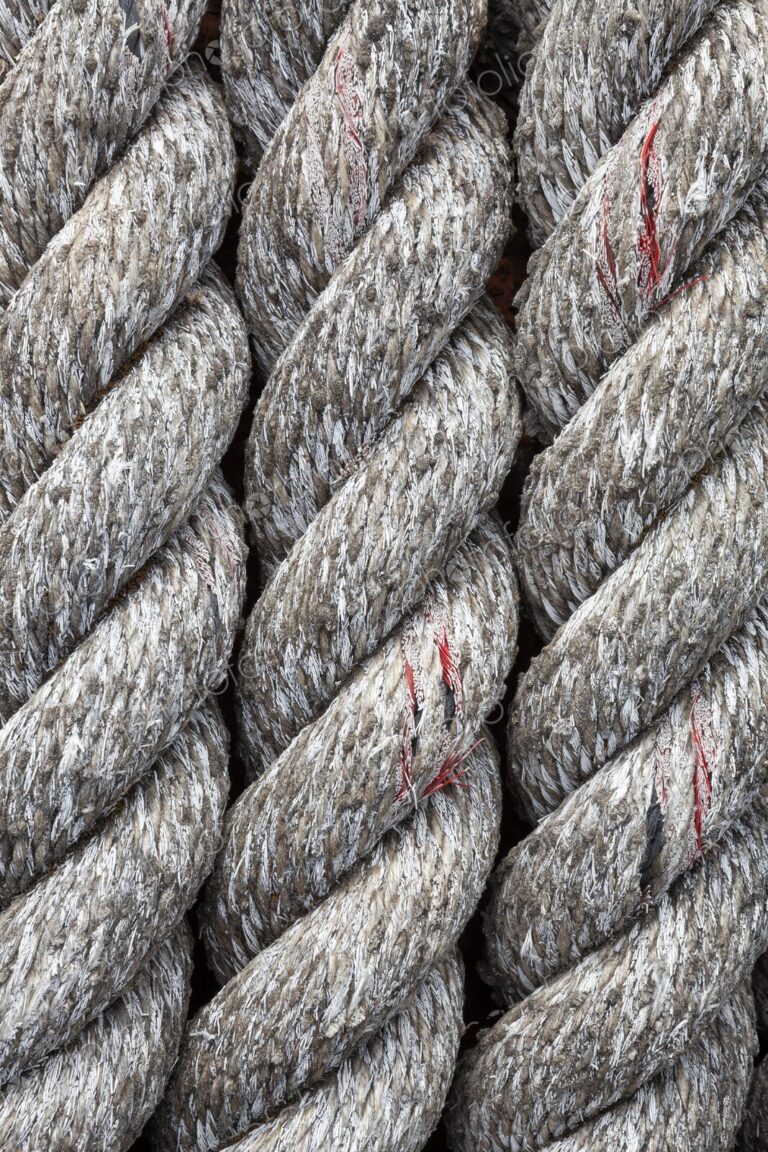 Detailed close-up of thick, weathered rope at a marina in Bandon, Oregon, showing…