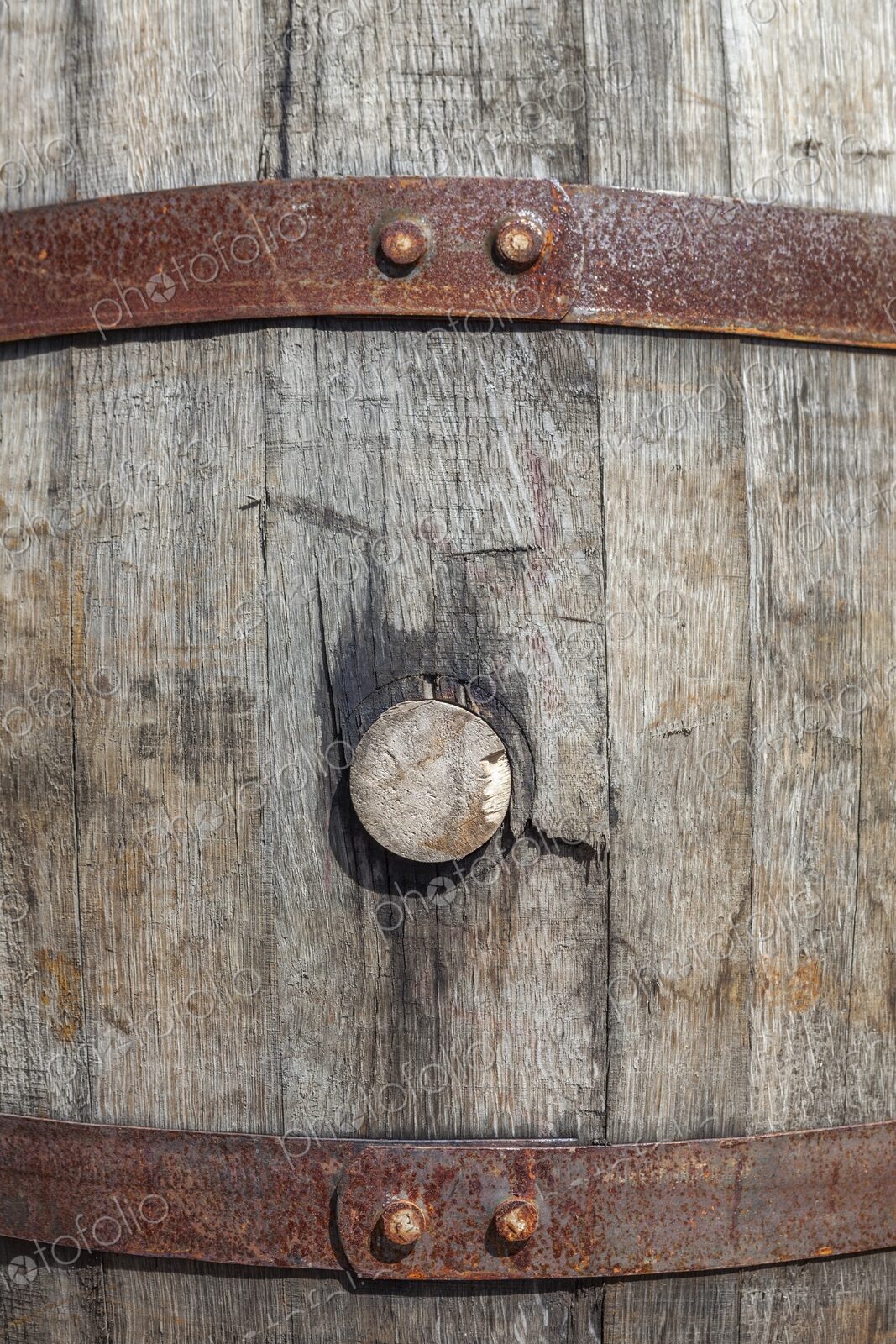 Detailed view of a weathered wooden barrel with cork, secured with rusted iron bands,…