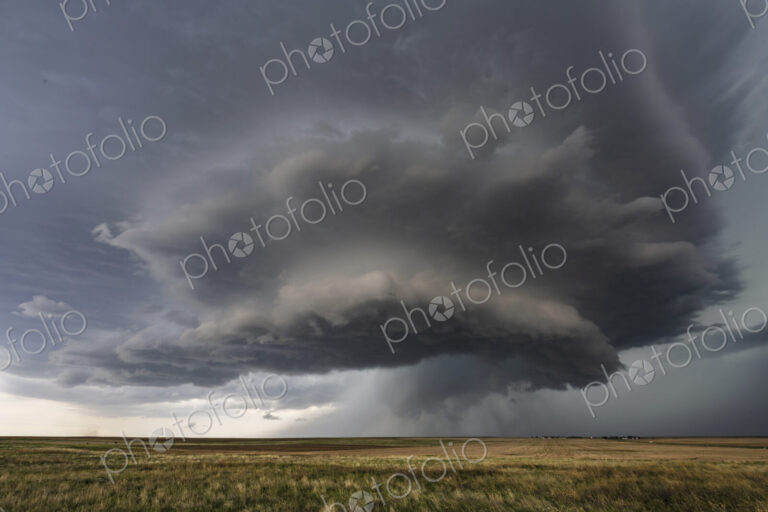 Developing Mesocyclone, a towering two layer shape above the horizon, storm clouds…