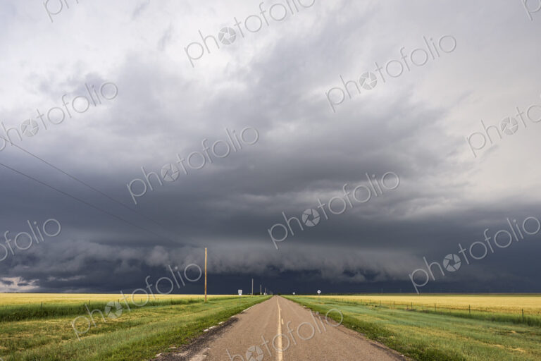 Developing Supercell storm on the horizon, black clouds at the end of a highway.
