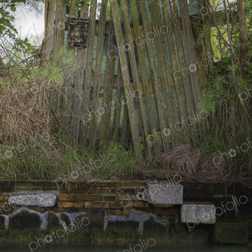 Dilapidated wooden fence on canal watefront. Dilapidated wooden fence on canal watefront.