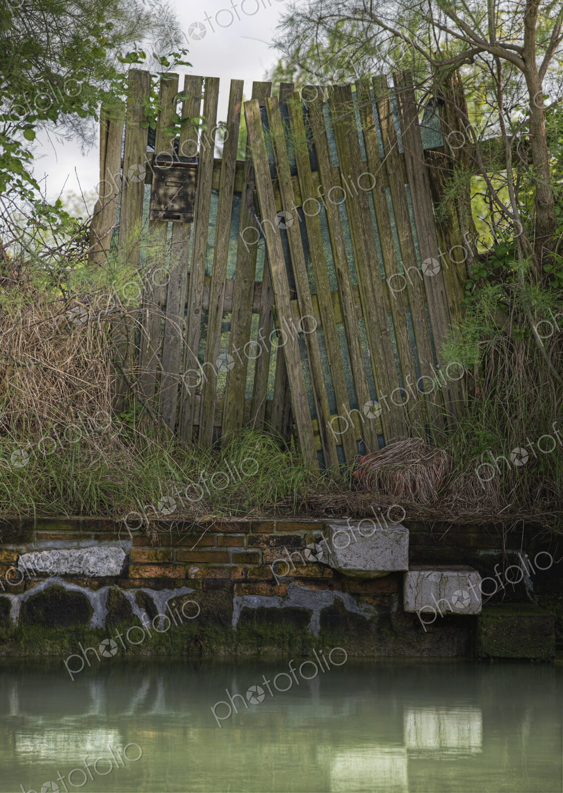 Dilapidated wooden fence on canal watefront.