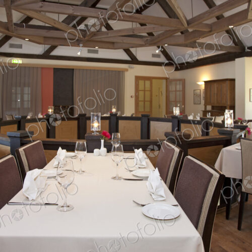 Dining room, tables laid for dinner on a mezzanine floor, exposed beams and vaulted…
