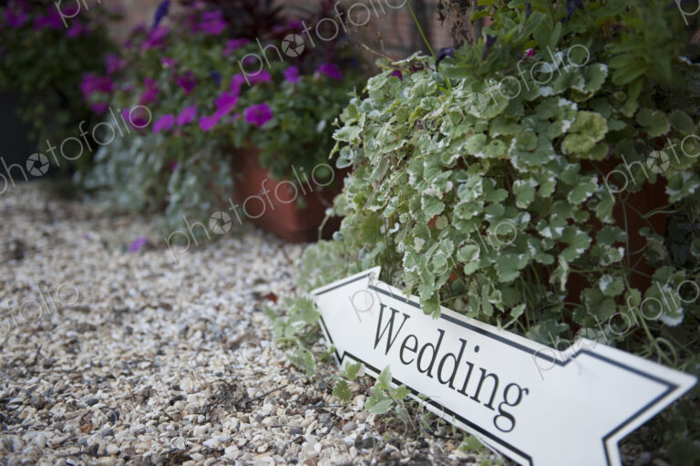 Directional sign to a wedding, on a gravel path.