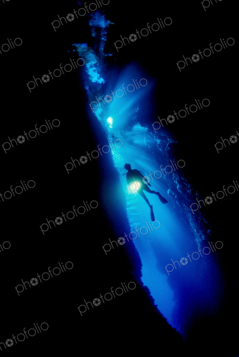 Diver silhouetted against the entrance to an underwater cave, Solomon Islands.