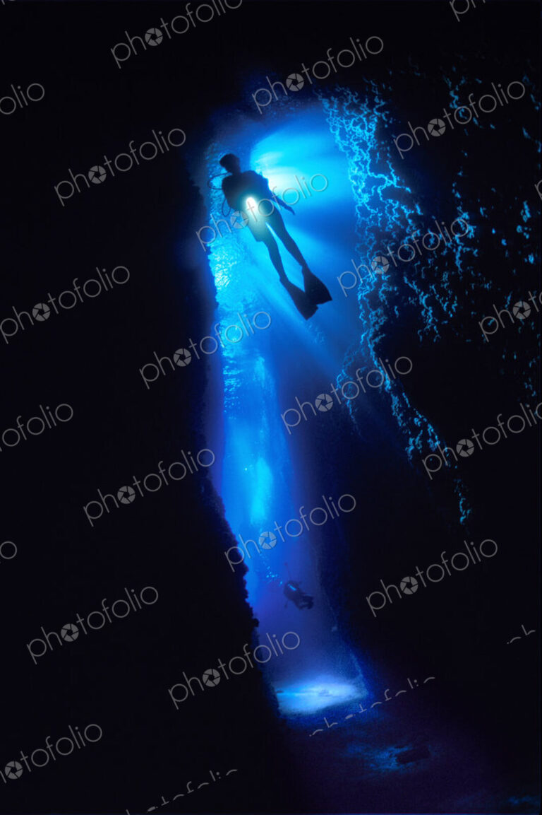 Diver silhouetted against the entrance to an underwater cave, Solomon Islands.