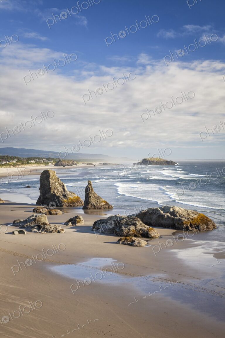 Dramatic sea stacks rise from the sandy shoreline of Bandon Beach, Oregon, with waves…