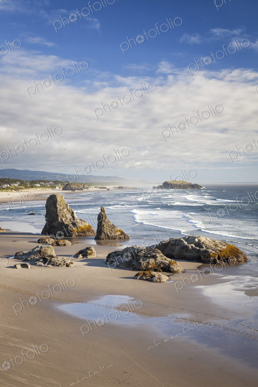 Dramatic sea stacks rise from the sandy shoreline of Bandon Beach, Oregon, with waves…