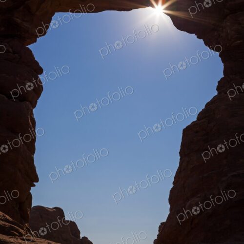 Dramatic view of the sunburst shining through a natural rock arch (Turret Arch) in… Dramatic view of the sunburst shining through a natural rock arch (Turret Arch) in…