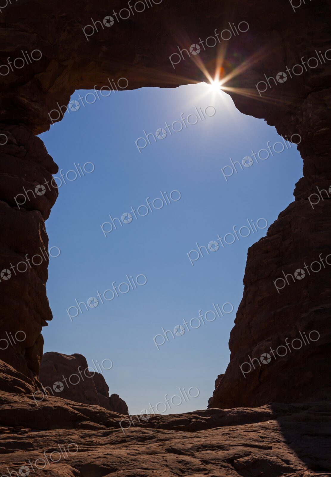 Dramatic view of the sunburst shining through a natural rock arch (Turret Arch) in…