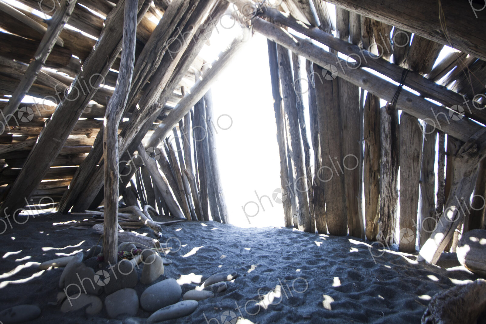 Driftwood hut interior on sand.