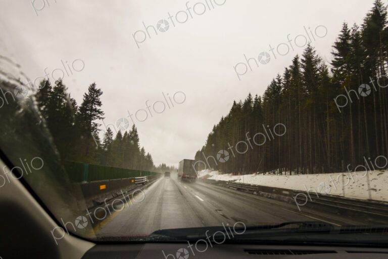 Driver's perspective through windshield of winter highway with semi-truck.