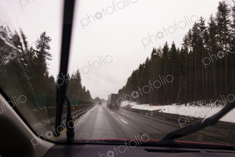 Driver's perspective through windshield of winter highway with semi-truck.