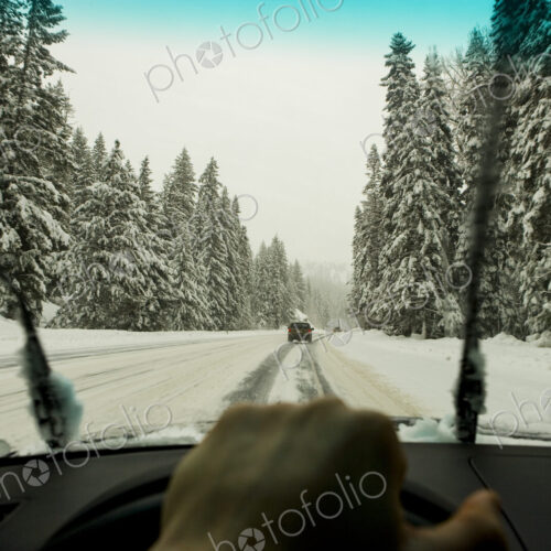 Driver's view through the windscreen of a snowy road and cars driving, a driver's hand… Driver's view through the windscreen of a snowy road and cars driving, a driver's hand…