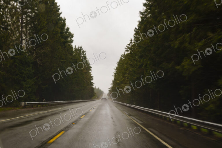 Driver's view through windshield of wet highway in rural area, WA, USA
