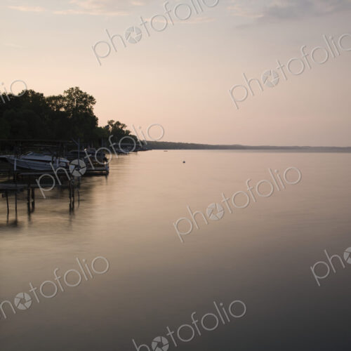 Dusk, view across calm water in the Finger Lakes area, New York State, USA, shoreline… Dusk, view across calm water in the Finger Lakes area, New York State, USA, shoreline…