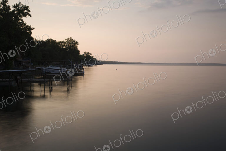 Dusk, view across calm water in the Finger Lakes area, New York State, USA, shoreline…