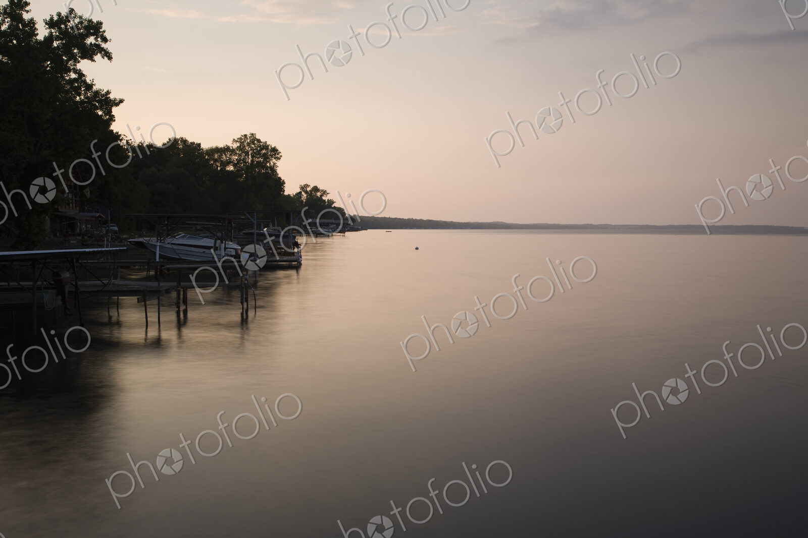 Dusk, view across calm water in the Finger Lakes area, New York State, USA, shoreline…