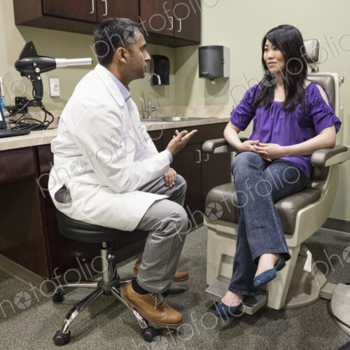 East Indian male ophthalmologist working with a female patient in his examination office. East Indian male ophthalmologist working with a female patient in his examination office.