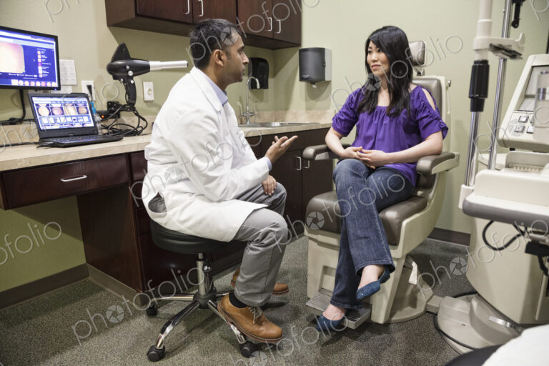 East Indian male ophthalmologist working with a female patient in his examination office.