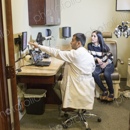 East Indian male ophthalmologist working with a female patient in his examination office. East Indian male ophthalmologist working with a female patient in his examination office.