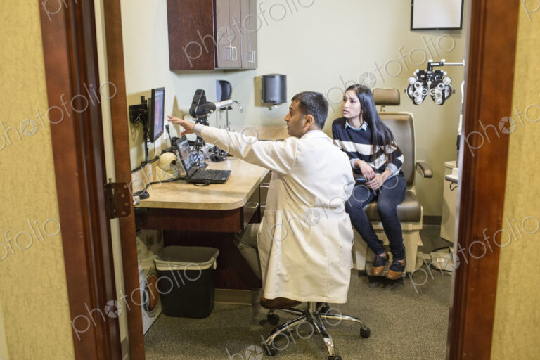 East Indian male ophthalmologist working with a female patient in his examination office.