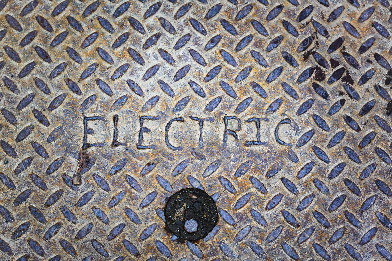Electric man hole cover close up, a metal surface.