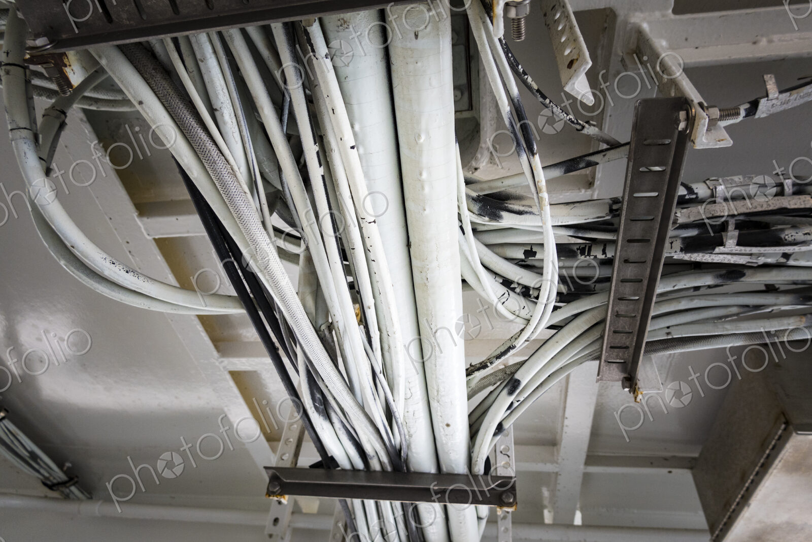 Electrical cables running along the ceiling of a ferry cabin ceiling, the wiring on a…