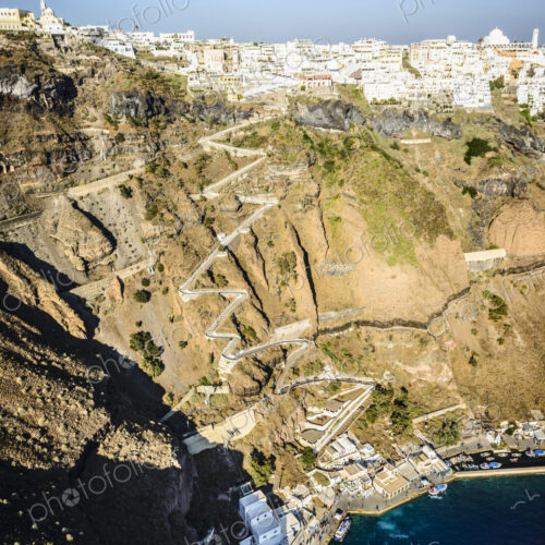 Elevated view of a steep cliff, hilltop town and a harbour on the water with a zigzag… Elevated view of a steep cliff, hilltop town and a harbour on the water with a zigzag…