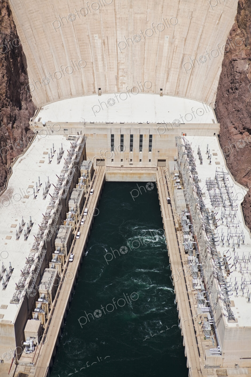Elevated view of the Hoover Dam wall, buildings and the water pool at the base of the…