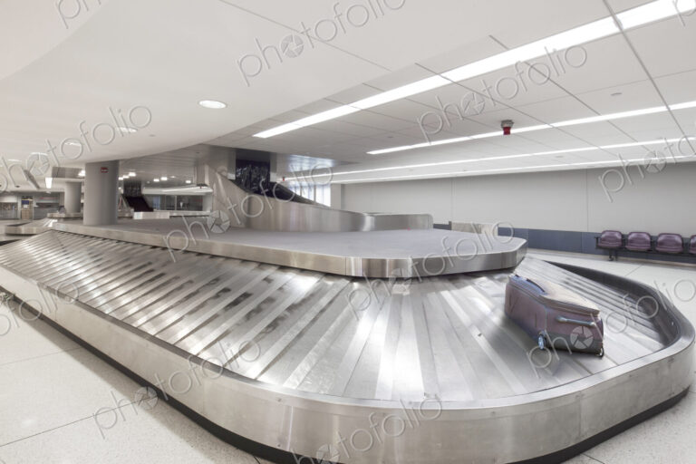 Empty airport luggage claim area, a single bag on a carousel.