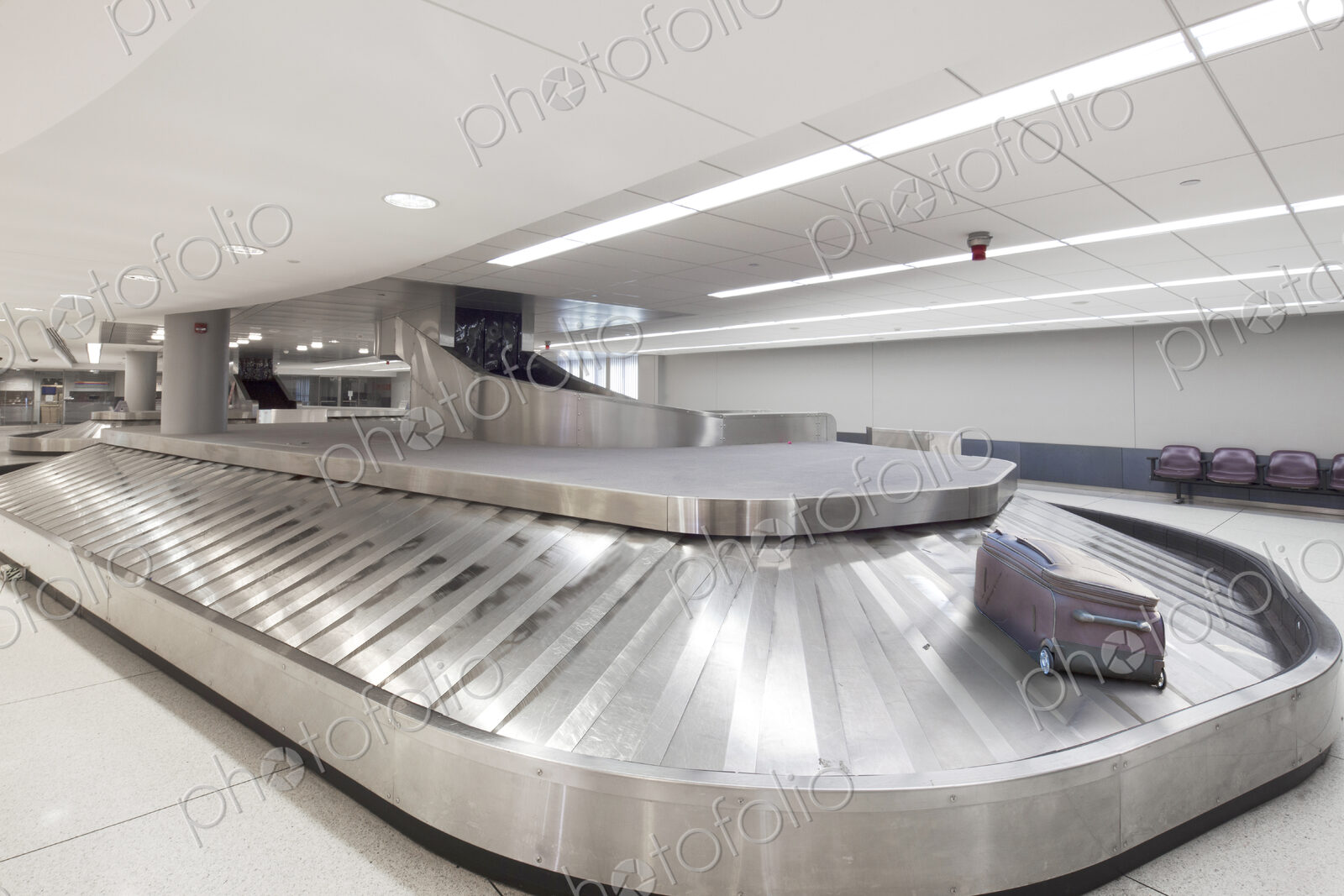 Empty airport luggage claim area, a single bag on a carousel.