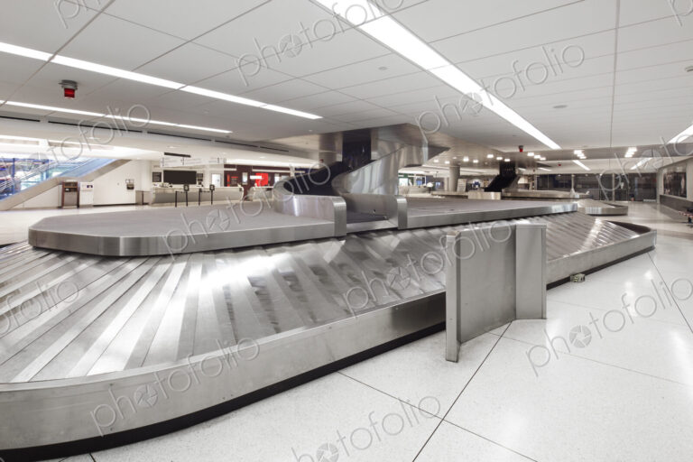 Empty airport luggage claim area, carousels and information screens.