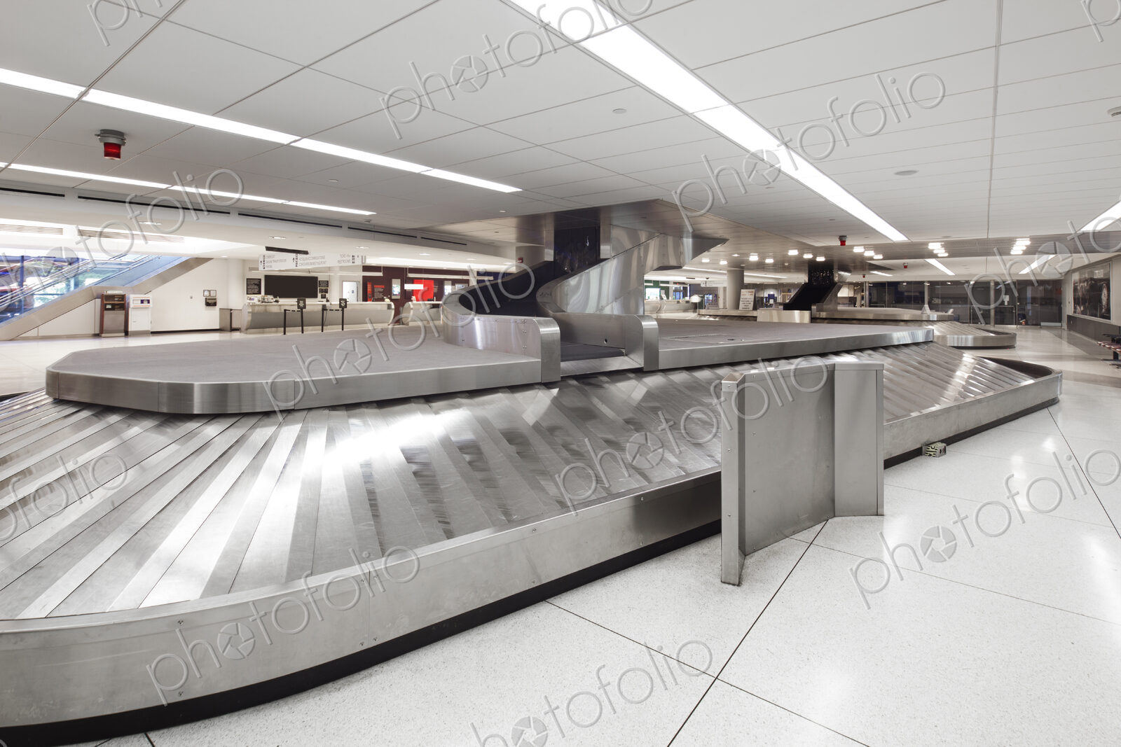 Empty airport luggage claim area, carousels and information screens.