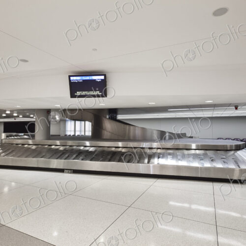 Empty airport luggage claim area, carousels and trolleys.