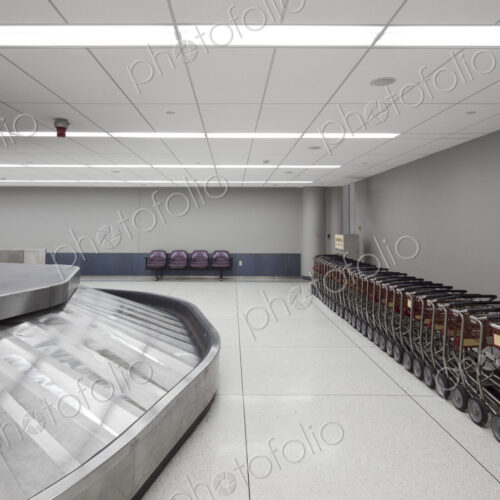 Empty airport luggage claim area, carousels and trolleys.