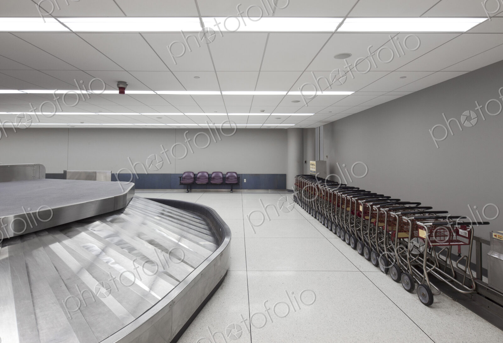 Empty airport luggage claim area, carousels and trolleys.